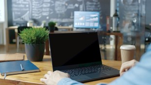 male-office-worker-at-his-desk-works-on-a-laptop-with-mock-up-green-screen-over-the-shoulder-close-up-footage-in-the-background-creative-office-79091780f1